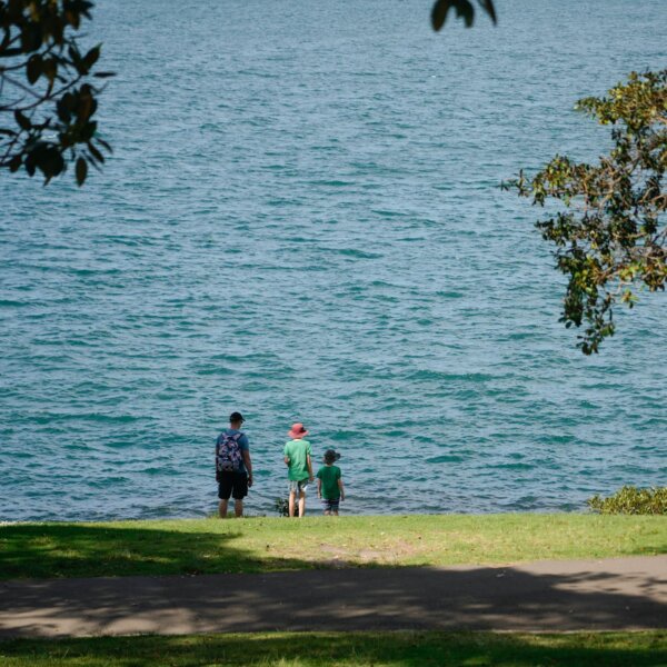 A family enjoying a peaceful walk by the lake on a sunny summer day.