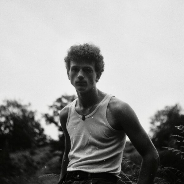 Monochrome photo of a man in a tank top outdoors with a vintage feel.